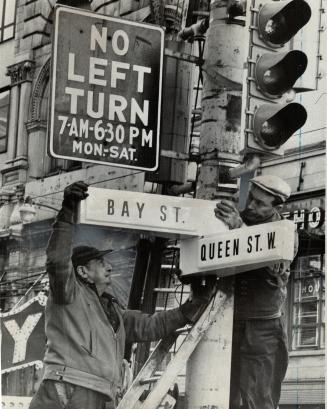 First lighted signs. Joe Townsend (left) and Charles McKenzie of the Department of Public Works today put up the first of Toronto's new illuminated street signs