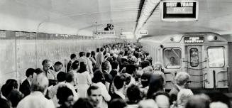 Subway passengers crowd onto the platform at the Queen St