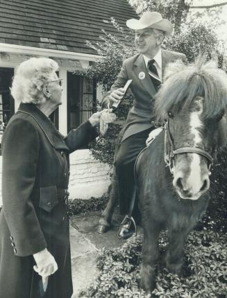 Marion Catto of Plymbridge Dr., North York, holds a carrot in her right hand - a donation for the horse - after giving her United Appeal donation to B(...)