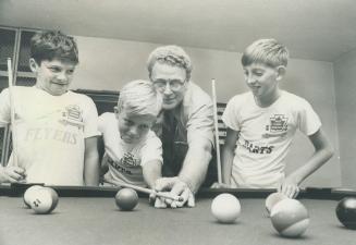 Straightening out his aim, Dave Nelson, director of the Metropolitan Downtown Boys' Club, gives 12-year-old Terry Jackson some pointers on playing poo(...)