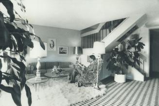 Image shows an interior of the apartment with the stairs on the right. The person is sitting on ...