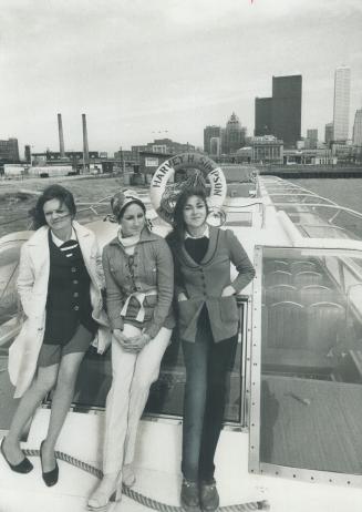 Image shows three university students on the boat with the Harbour buildings in the background.