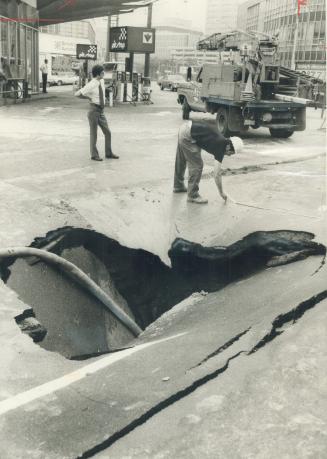 Image shows a hole in the street caused by watermain burst.