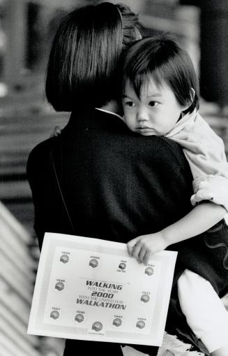 Walking Papers: A weary jacqueline Lau, 3, rests in her mother Grace's arms, clutching the certificate given to people yesterday at the United Way Walkathon