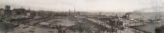 A black and white panoramic photo of the city in 1907. In the foreground are rooftops. A large  ...