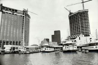 Image shows ferries at city docks with high rise buildings under construction. 