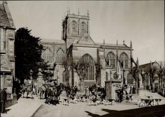 A picturesque scene from Dorsetshire, England, showing the Blackmore Vale Hounds passing Sherborne Abbey on their way to a covert just west of the town