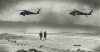 Grenada scene: Helicopters approach a landing strip while soldiers walk along beach