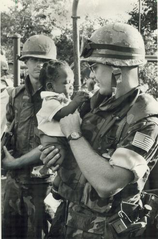 Friendly moments: A U.S. troop cuddles a Grenadian baby after the invasion of the Island by a U.S.-led task force. But American civil liberties expert(...)