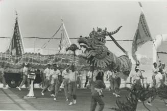 Celebrating a holiday in Chinese style, a group of youths bearing a large paper mache dragon parade along Hong Kong waterfront