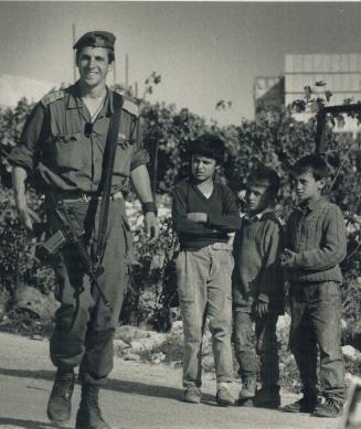 Smiling Soldier: An Israeli trooper passes Palestinian children in the West Bank
