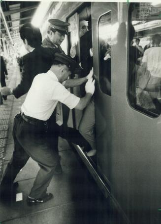An oshiya (pusher) is needed to cram passengers into a commuter train during rush-hour in crowded Tokyo