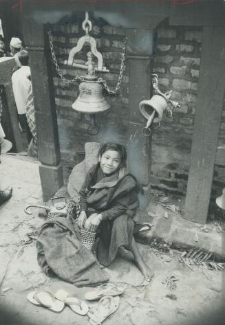 High in the Himalayas a youngster plays beside the temple bells at the shrine of Kali, goddess of retribution