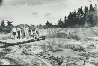 Group of tourists to Rotorua on North Island have a close-up view of sulphur hot springs