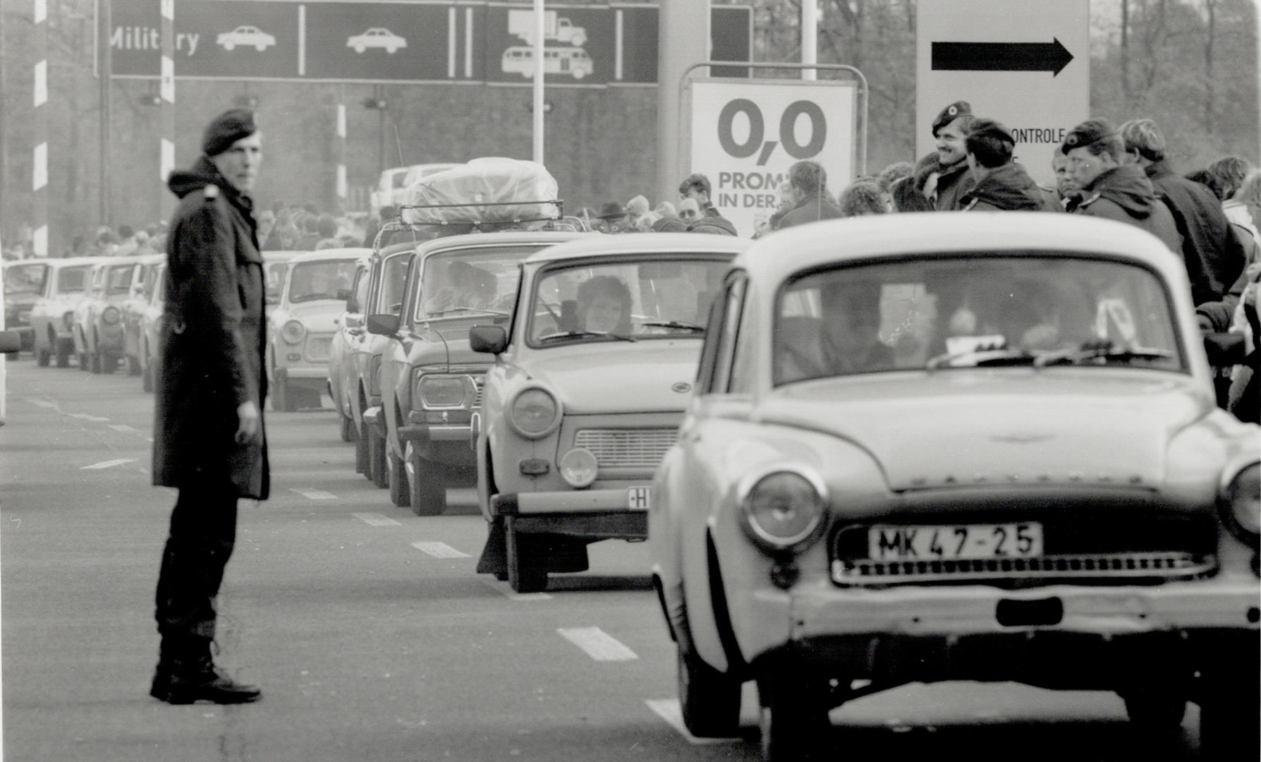A west German border policeman stands aside as a stream of East Germans arrive in the west