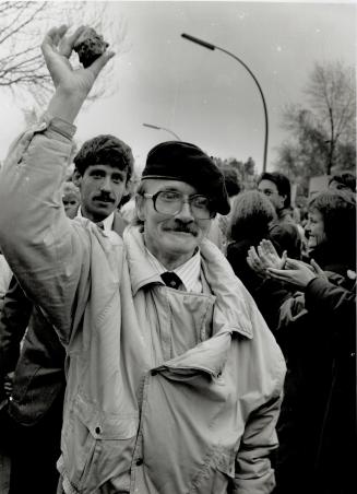 An East German holds up a brick of the Berlin Wall after he had crossed the border of the divided town over the new border crossing at Potzdam Place Nov. 12