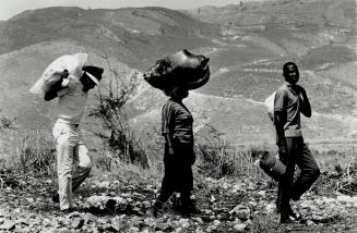 At right, Haitians returned from the United States trudge through the parched countryside back to their village
