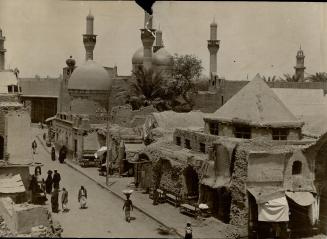 A new street, with modern paving and curb, slices through the ancient, crowded north quarter of Bagdad, leading to the Mosque of Kauzemain. The buildi(...)