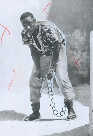 Freedom's end: On infamous Goree Island, off Dakar in Senegal, a guide demonstrates the ankle and wrist chains that were used to secure some of the 20 million slaves who passed through the port