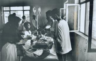 Primitive Hospital: Somall surgeons work on a patient in a living room that has been turned into an operating theatre