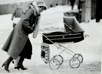 Bringing home the rations: A Polish mother pushes her baby carriage through wind-swept streets, toting the large bag that most Poles carry in hopes that they will find goods in the stores