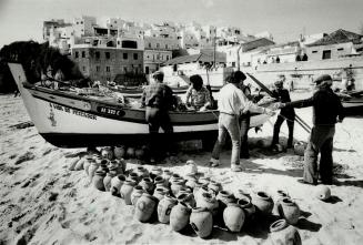 Fishermen tend to their nets on the Algarve coast in Portugal, one of Europe's great bargains