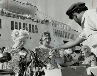 Dockside bargaining for souvenirs is one of the standard pastimes for cruise passengers, though these two don't appear to like the prices. At right a happier group enjoys a day afloat in the sun
