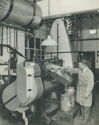 A three-roller mill in operation in The Star's ink department, producing red ink for use in The Star Weekly magazine section. The red pigments are gro(...)
