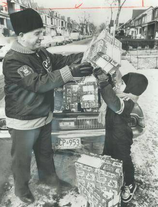 Helping Santa's helper, 5-year-old Michael Grisz assists Carmen Bush, director of the Columbus Boys' Club, in loading Bush' car with parcels for the n(...)