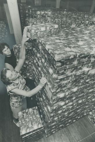 Star Santa Claus boxes are piled high by Ann Meek (rear) and Violet Sinclair, two of the gnomes who are packing gifts for 24,000 needy children in Met(...)