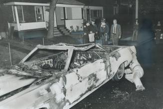 Detectives and Firemen check the charred wreckage of the 1971 convertible owned by Len Addison, general manager of the Toronto Humane Society, which w(...)