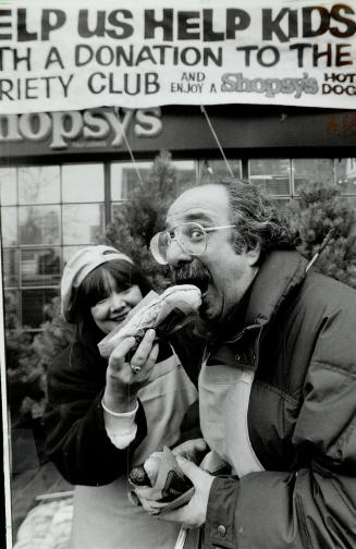 Two-fisted eater. Actor Harvey Atkin tucks into hot dogs, as City-TV's Brona Brown looks on, during a celebrity outdoor barbecue yesterday to raise mo(...)