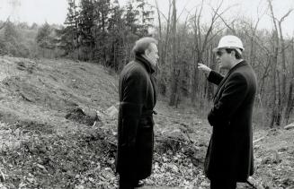 Image shows two gentlemen talking surrounded by some trees.
