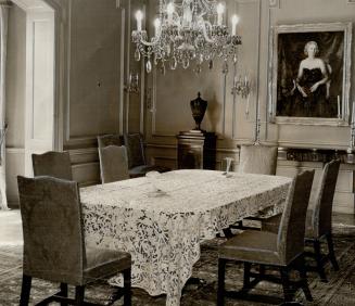 Returning upstairs, the walnut-finished dining room meets the eye, with its long table covered with a fine lace cloth and its elegant crystal chandelier