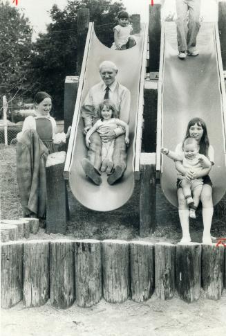 Attorney-general Dalton Bales takes a slide with 3-year-old Debbie Simkins in the adventure playground opened Saturday at Spring Garden Public School,(...)