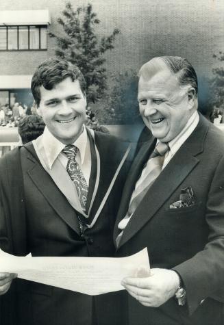 The president of Maple Leaf Gardens, Harold Ballard, and his son Bill look at diploma young Ballard received yesterday at the spring convocation of Yo(...)