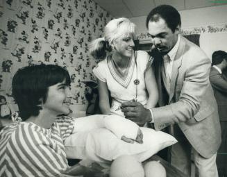 Fifteen-year-old patient Darcy Azzopardi beams as baseball star Reggie Jackson signs his cast and tennis whiz Carling Bassett looks on. The sports cel(...)