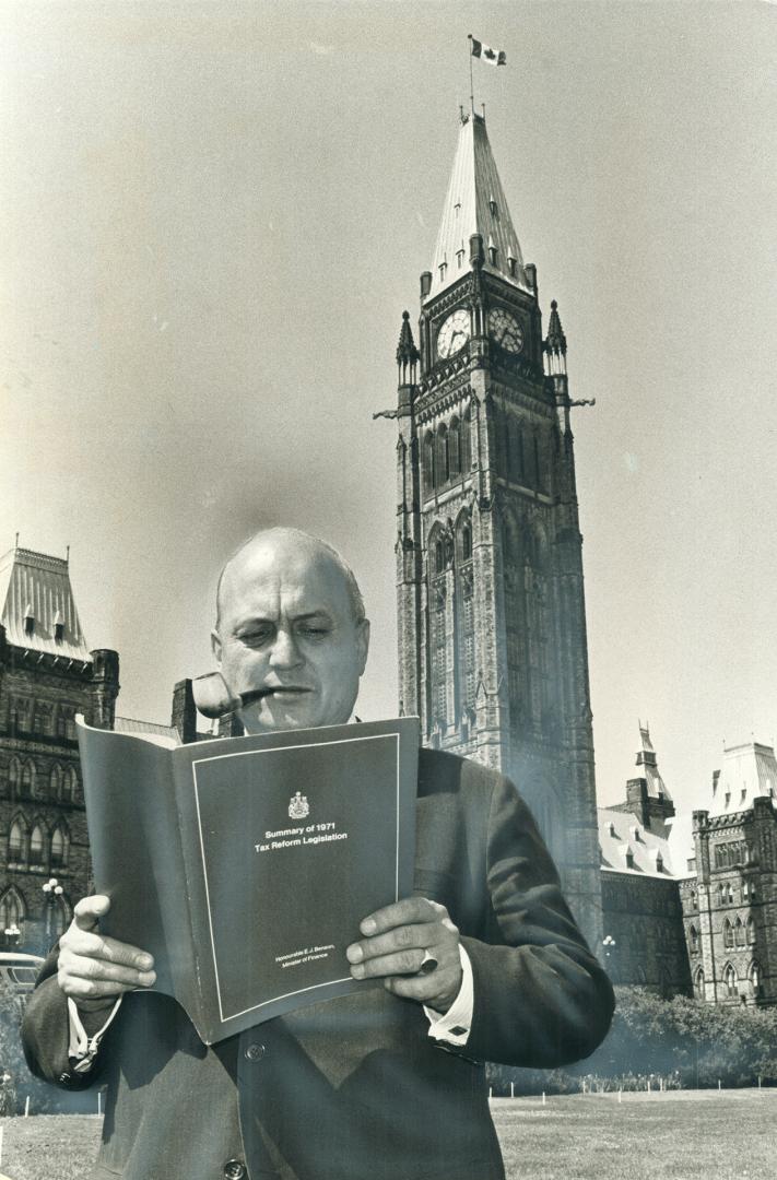 Finance Minister Edgar Benson stands outside the House with copy of tax bill he introduced to Commons on Friday