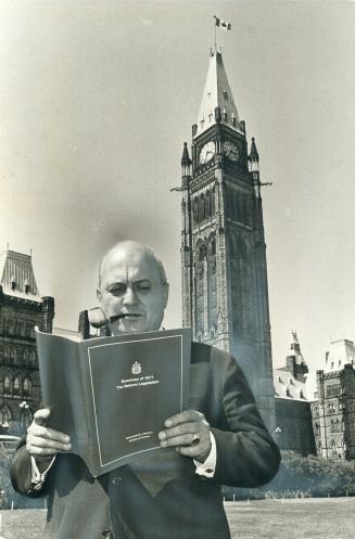 Finance Minister Edgar Benson stands outside the House with copy of tax bill he introduced to Commons on Friday
