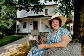Country home: Janet Berton, wife of author Pierre Berton, sits in front of the historic Kline/Howland house in Kleinburg, the town where they have lived for 38 years