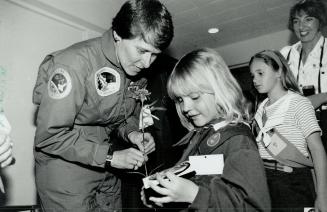 Fair exchange: Astronaut Dr. Roberta Bondar gives a NASA decal to Sara, a Brownie, who presented her with a flower at Girl Guide headquarters yesterday