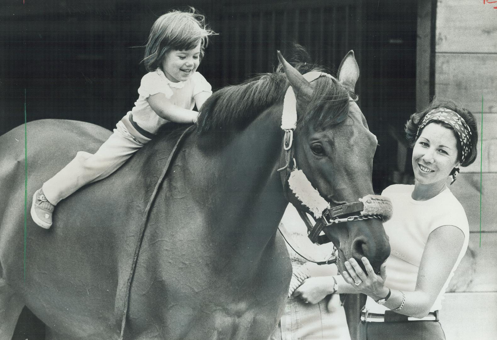 That's no child's pony: Two-year-old Christa-Dora Boylen tries out her mother's horse, Love Conquer, during a break from training at the Olympic equestrian events site in Bromont, Que