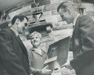 Diver Beverley Boys, honored by hometown of Pickering last night, displays color photograph mounted on shield showing her in action at Mexico Olympics. [Incomplete]