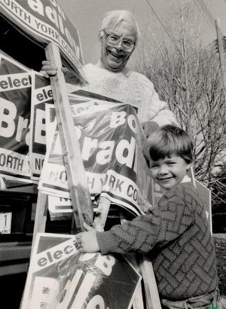 Bob Bradley, left, the elected Ward 13 councillor, gets some help from his grandson Paul, 4, in clearing up election signs