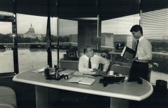 Top of the hill: In his office overlooking Capitol Hill, Ambassador Derek Burney is briefed on developing issues by executive assistant Ron Wall