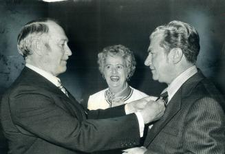 Simpsons chairman Allan Burton straightens Ira Reid's tie, while Mrs