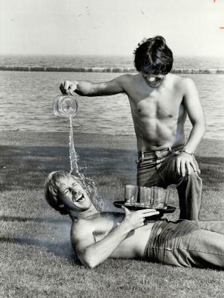 Water torture? Brian Budd (getting wet) and Ray Treacy, a couple of self-confessed crazies, beat the heat in a park across from their Lakeshore Blvd. (...)
