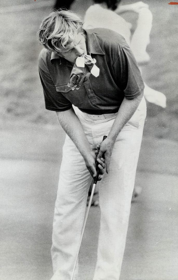 Glove in mouth, Canadian Amateur leader George Burns practises putt