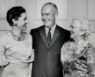 East meets west as Edgar G. Burton, president of the Robert Simpson Co. Ltd., greets two new members of the company's 25 Year club. At left is Mrs. Fl(...)