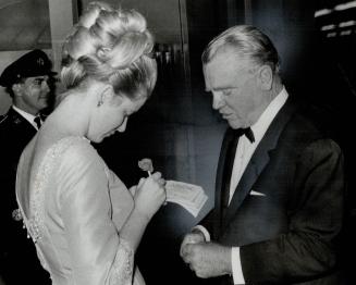 Up from hollywood came Mr. and Mrs. James Cagney. Here the actor buys tickets from Miss Bobby MacBrien to support the Canadian equestrian team. Cagney(...)